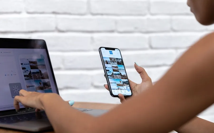 Hands using a social media scheduling app on a laptop and smartphone, with a grid of queued photo posts