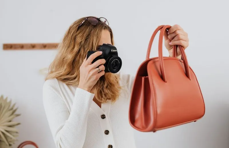 Woman photographing a leather handbag with a DSLR camera for product photos